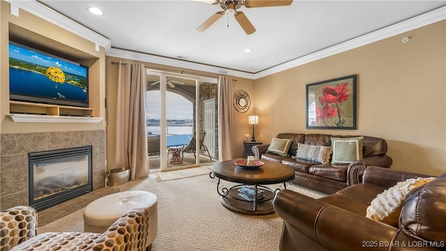 carpeted living room with ornamental molding, a tile fireplace, ceiling fan, and a water view