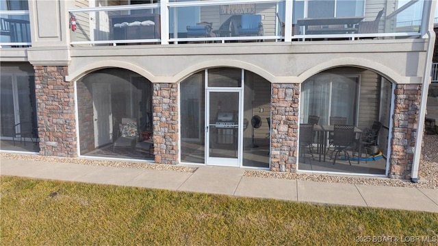 doorway to property featuring a yard and a balcony