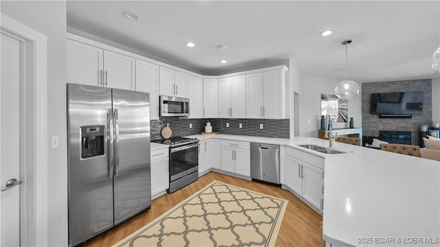 kitchen featuring light wood-type flooring, stainless steel appliances, sink, and white cabinets