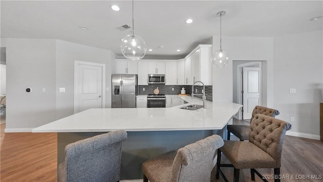 kitchen with white cabinetry, stainless steel appliances, sink, and hanging light fixtures