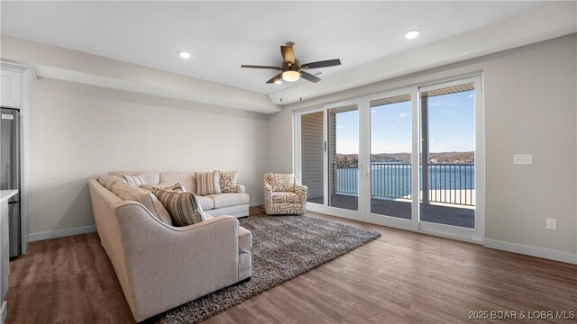 living room featuring a water view, ceiling fan, and dark hardwood / wood-style flooring