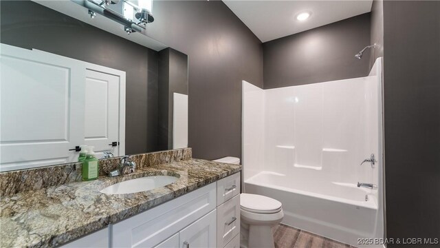 full bathroom featuring hardwood / wood-style flooring, vanity, shower / bathing tub combination, and toilet