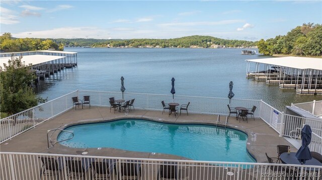 view of swimming pool with a dock, a patio, and a water view