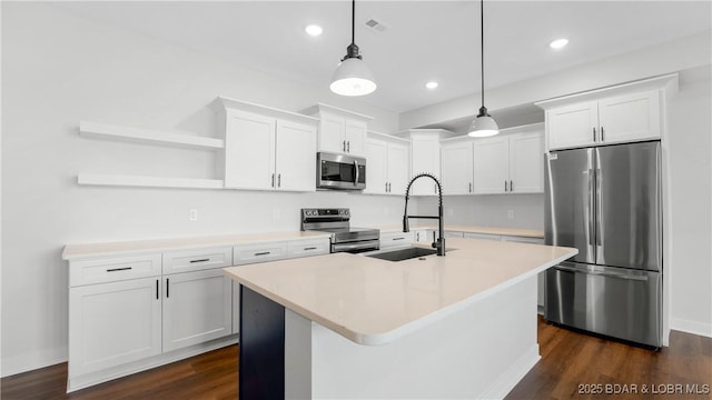 kitchen with sink, stainless steel appliances, white cabinets, a center island with sink, and decorative light fixtures