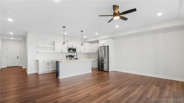 kitchen with dark hardwood / wood-style floors, pendant lighting, stainless steel appliances, a kitchen island with sink, and white cabinets