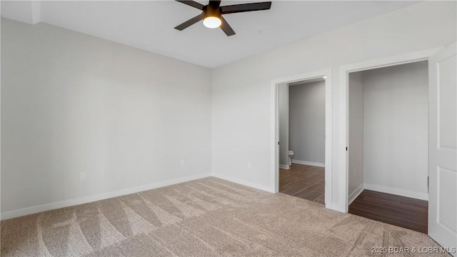 unfurnished bedroom with ceiling fan and dark colored carpet