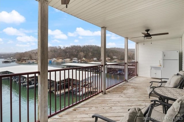 deck with a water view, a boat dock, and ceiling fan