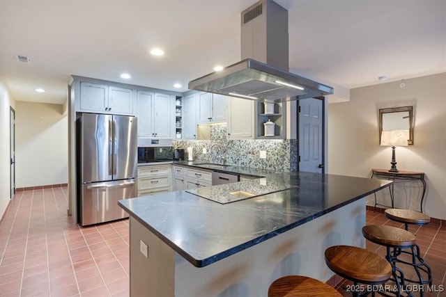 kitchen with a breakfast bar area, appliances with stainless steel finishes, white cabinetry, island exhaust hood, and kitchen peninsula