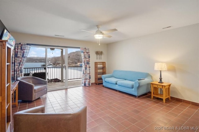 living room with a water view, ceiling fan, and tile patterned flooring