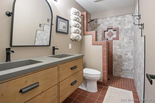 bathroom featuring vanity, toilet, tile patterned flooring, and a tile shower