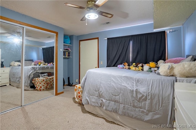 carpeted bedroom featuring ceiling fan, a closet, and a textured ceiling