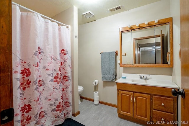 bathroom with walk in shower, vanity, and toilet