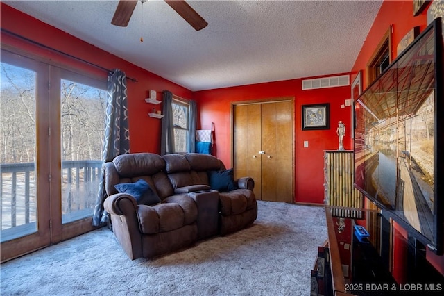 living room featuring ceiling fan, a textured ceiling, and carpet flooring