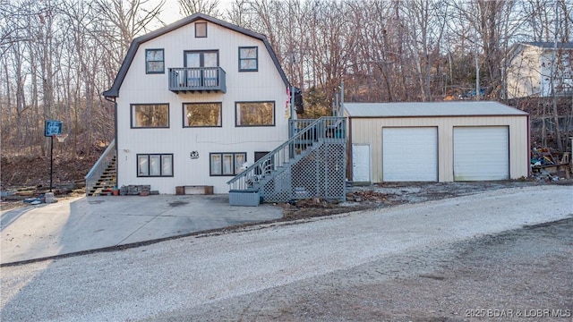 view of front of home with a garage, an outdoor structure, and a balcony