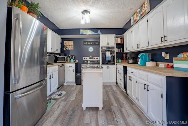 kitchen with light wood-type flooring, stainless steel appliances, white cabinets, and a kitchen island