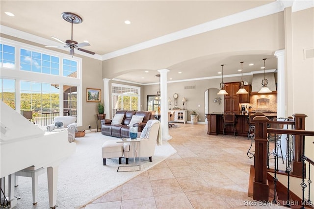 tiled living room with decorative columns, crown molding, and ceiling fan