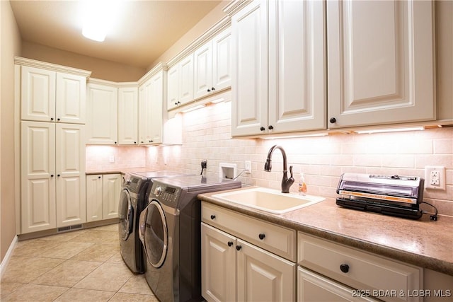 laundry room with washer and dryer, sink, light tile patterned floors, and cabinets