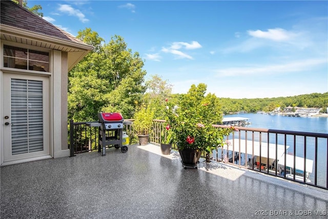 view of patio with a balcony, a water view, and a grill