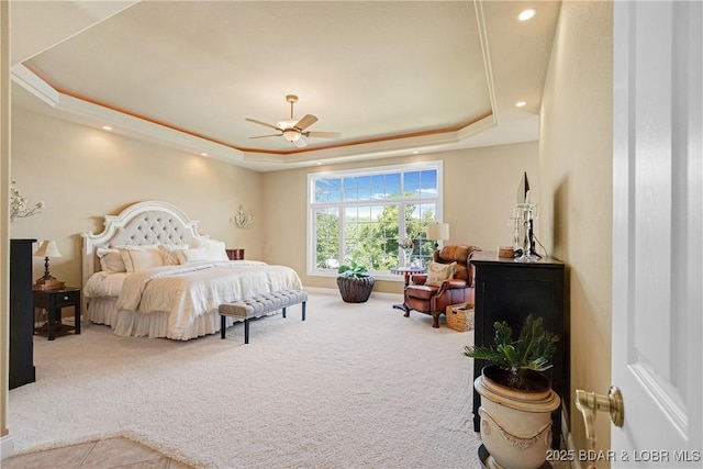 carpeted bedroom featuring ceiling fan and a raised ceiling