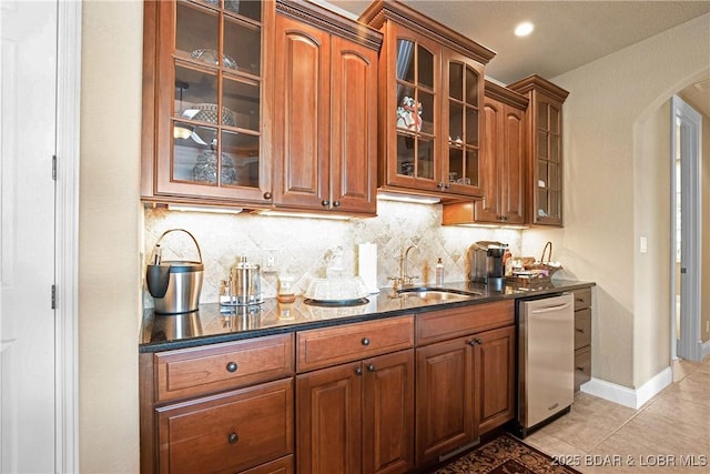 kitchen with stainless steel dishwasher, light tile patterned floors, sink, and backsplash