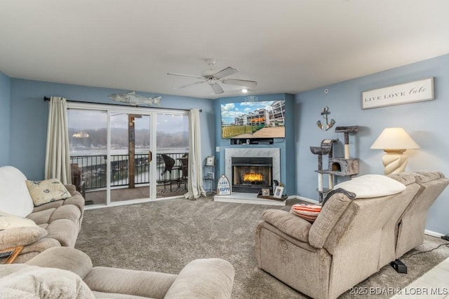 carpeted living room featuring a premium fireplace and ceiling fan