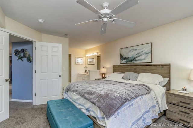 bedroom featuring ensuite bathroom, light colored carpet, and ceiling fan