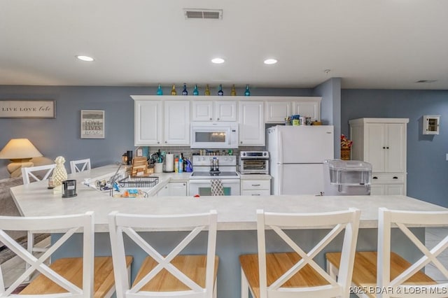 kitchen featuring sink, a breakfast bar area, white cabinets, and white appliances