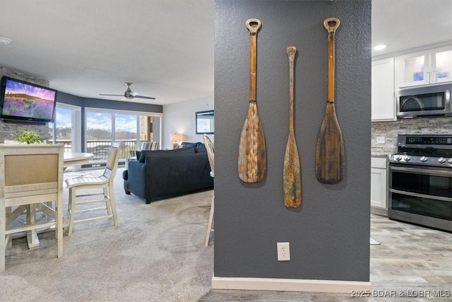 kitchen with appliances with stainless steel finishes, white cabinets, ceiling fan, and decorative backsplash