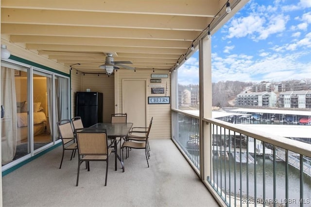 sunroom with a water view and ceiling fan