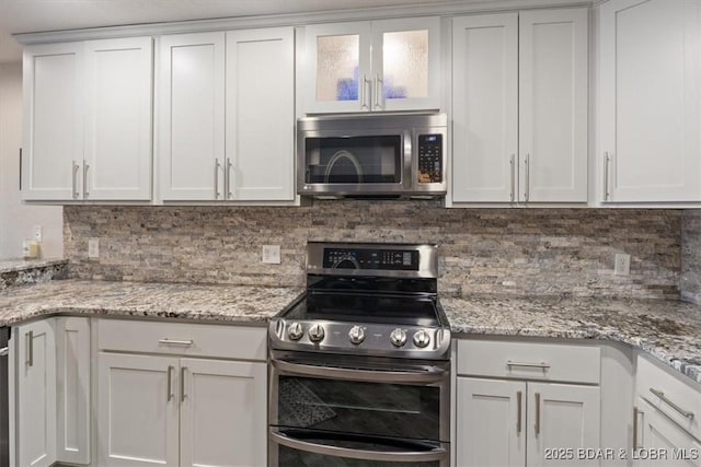 kitchen with backsplash, appliances with stainless steel finishes, light stone counters, and white cabinets