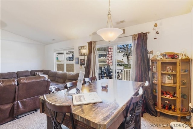 carpeted dining space with lofted ceiling and plenty of natural light