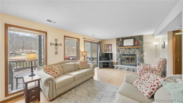 living room featuring a textured ceiling, a fireplace, and light hardwood / wood-style flooring