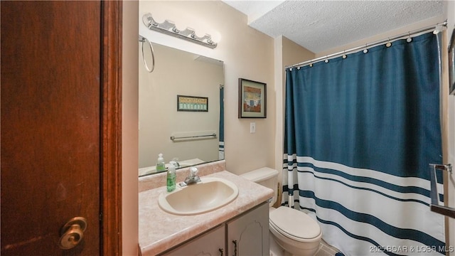 bathroom featuring walk in shower, vanity, toilet, and a textured ceiling