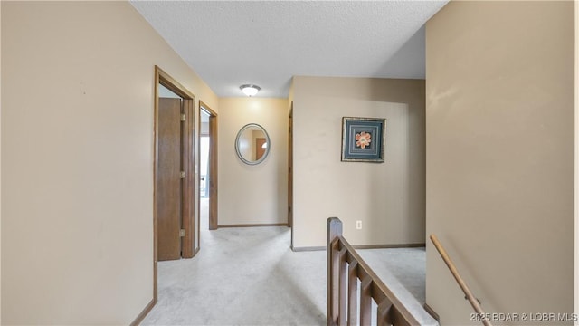 corridor featuring light carpet and a textured ceiling