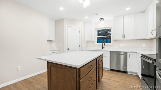 kitchen featuring sink, stainless steel appliances, a center island, light hardwood / wood-style floors, and white cabinets