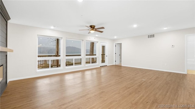 unfurnished living room featuring light hardwood / wood-style floors, a large fireplace, and ceiling fan