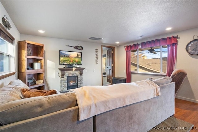 living room with wood-type flooring, a textured ceiling, and a fireplace