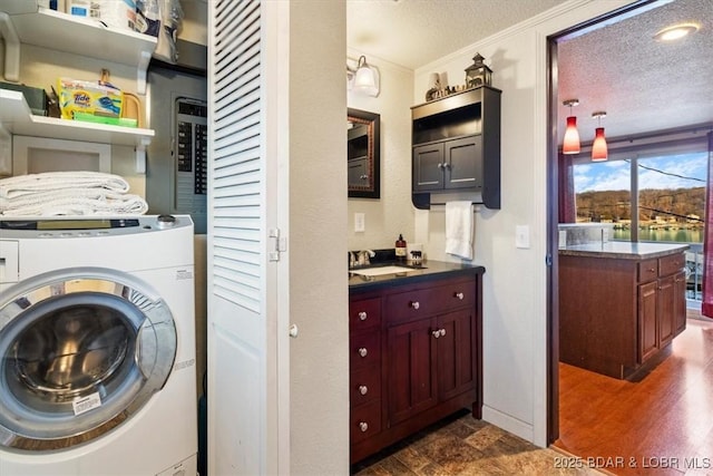 washroom featuring ornamental molding, washer / dryer, sink, and a textured ceiling