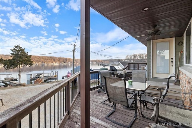 wooden deck with a water view and ceiling fan