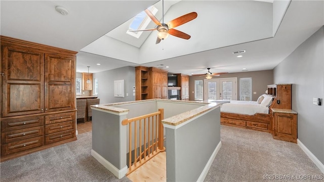 interior space featuring light colored carpet, vaulted ceiling with skylight, and a healthy amount of sunlight