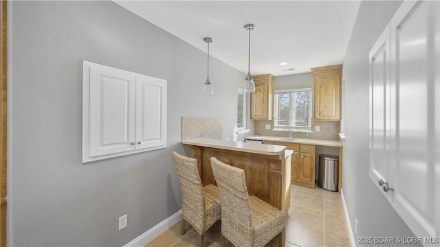 kitchen featuring pendant lighting, tasteful backsplash, kitchen peninsula, and light tile patterned flooring