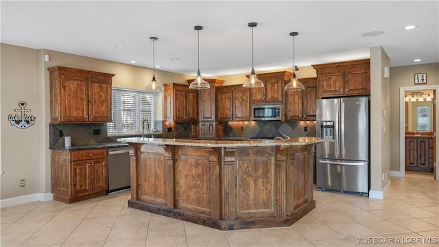 kitchen featuring stainless steel appliances, light stone countertops, a center island, and decorative light fixtures