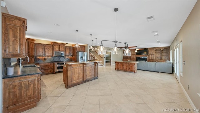 kitchen featuring pendant lighting, sink, appliances with stainless steel finishes, backsplash, and a kitchen island