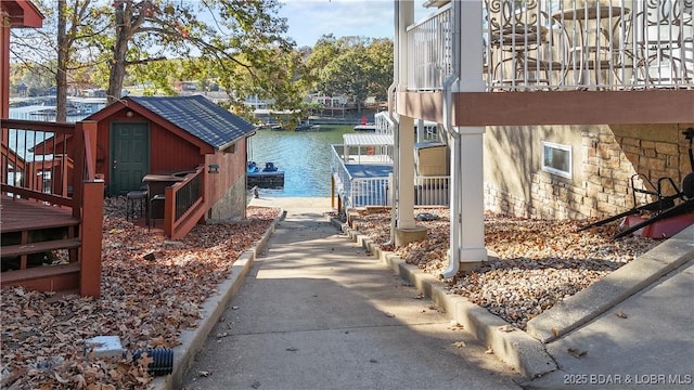 exterior space with a dock, a storage unit, and a water view