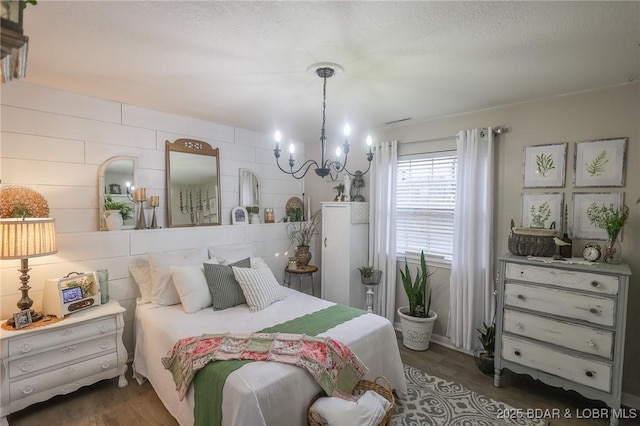 bedroom with dark wood-type flooring, a notable chandelier, and a textured ceiling