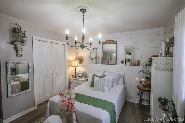 bedroom with dark wood-type flooring, a closet, a notable chandelier, and baseboards