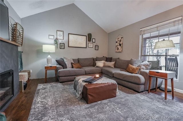 living room featuring high vaulted ceiling, dark wood-style flooring, and a glass covered fireplace