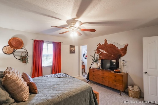 bedroom with ceiling fan, a textured ceiling, and light colored carpet