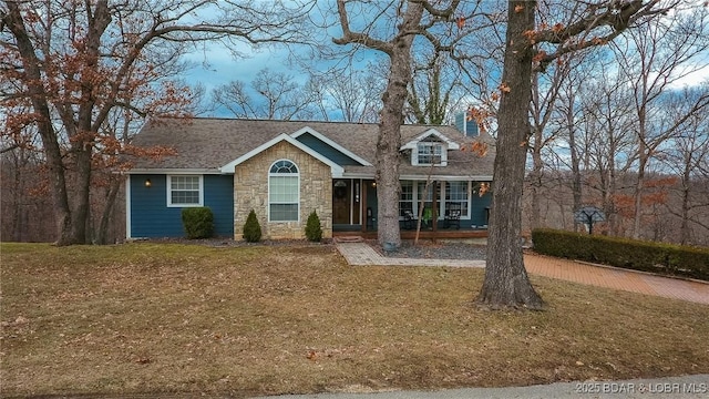 view of front of property with a porch, stone siding, and a front lawn