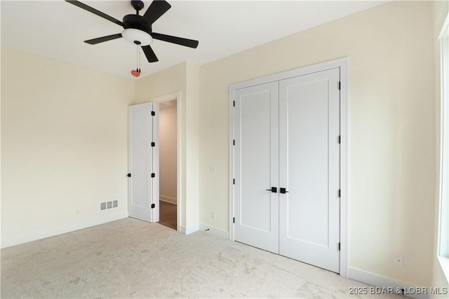 unfurnished bedroom with ceiling fan, light carpet, visible vents, baseboards, and a closet